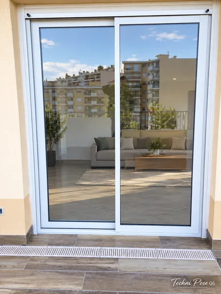 Baie vitrée coulissante blanche donnant sur une terrasse