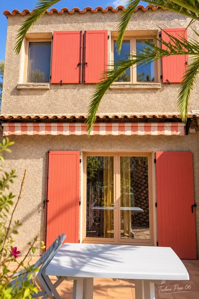 Volets rouges, fenêtres et store rayé sur une façade